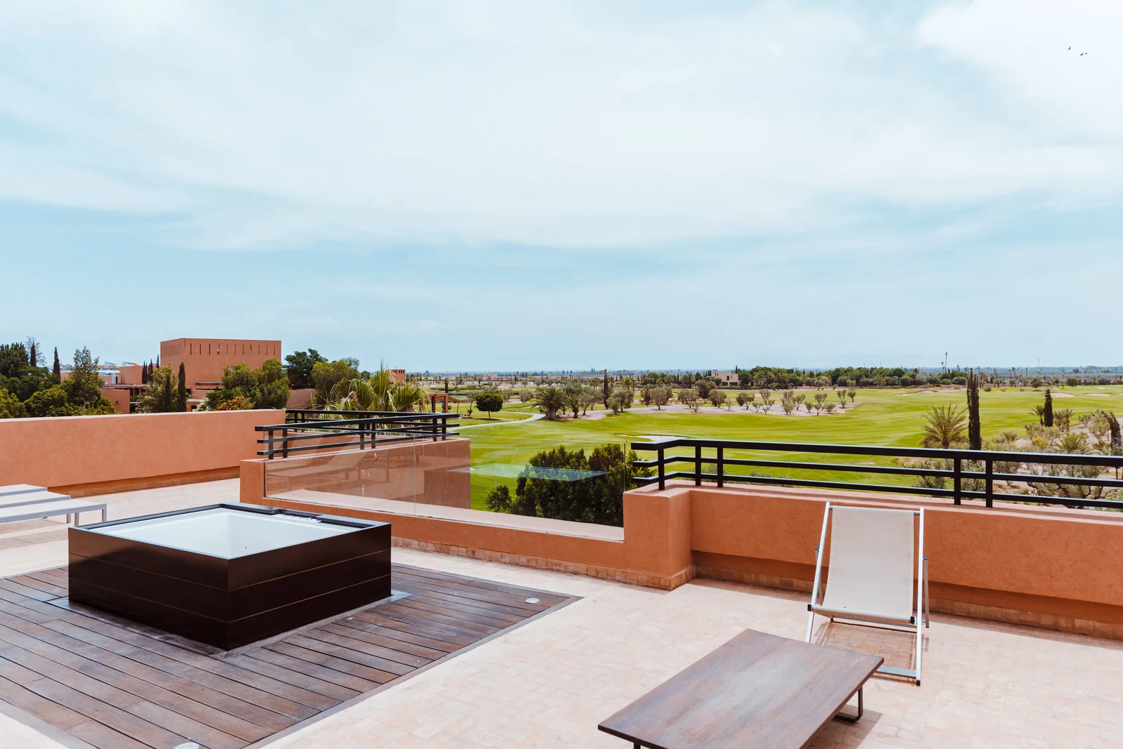 Rooftop terrace with sun loungers overlooking a green golf course in Marrakech